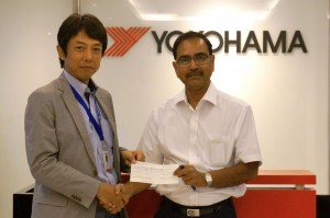 インド赤十字社のピー・シー・パルティハリ副長官（右）に義援金を手渡す藤津聡YIN社長