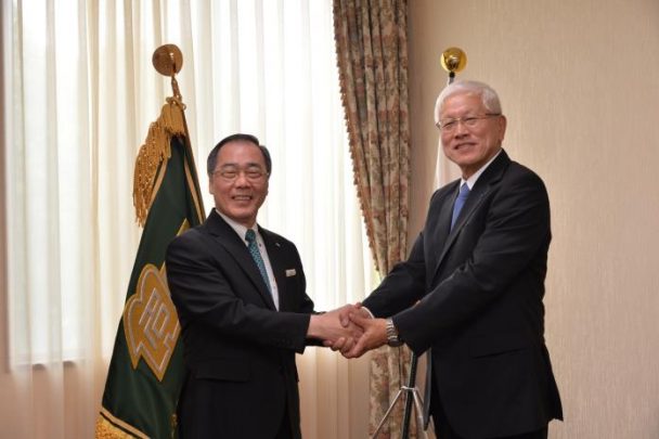 固い握手を交わす松尾総長（左）と松井社長