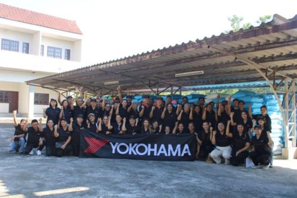 無償提供された肥料の前で記念撮影をする農家の方々