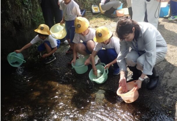 大北川で小学生と共にアユ稚魚を放流