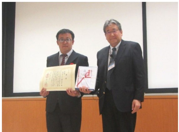表彰式の様子。左、受賞者の安川政宏氏